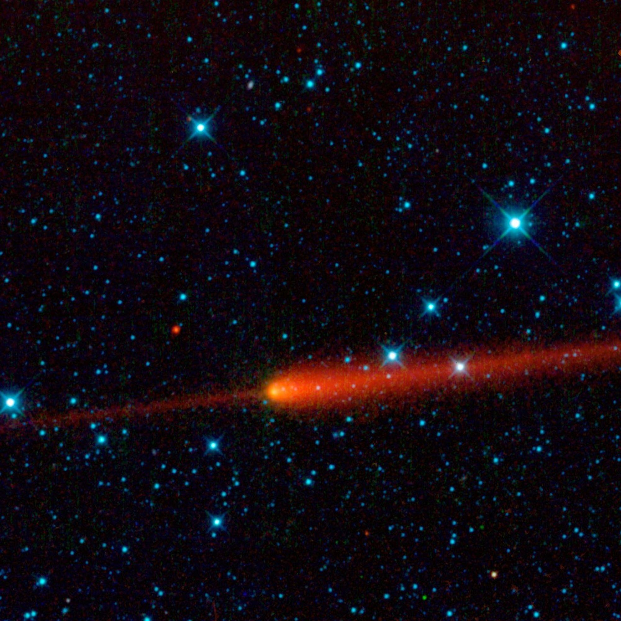 At the center of the image, a small glowing yellow ball is followed by what looks like a red-orange jet of flame extending symetrically behind it, toward the right and off the edge of the frame. Extending from the front of the yellow nucleus is a thin red-orange line, looking like a laser beam going off to the left and out of frame, in a direct line with the flame-like tail. Behind the comet is a star field, with the blackness of space dotted with points of light, colored light cyan and in various sizes. The exception is a few dots shining bright red – only five are easily visible.