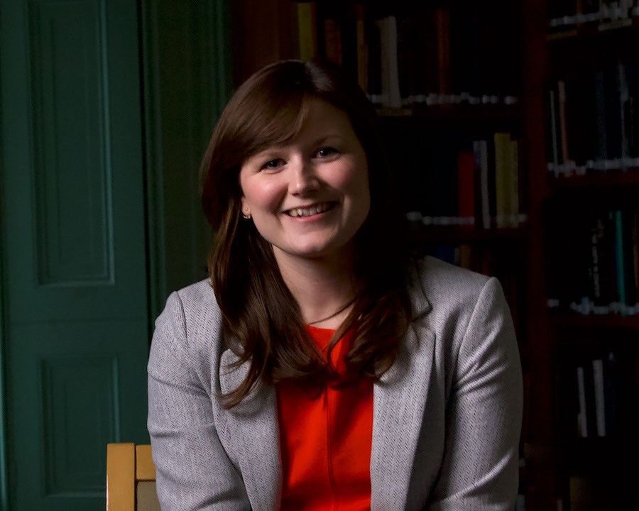 Portrait photo of a smiling woman against a dark black background