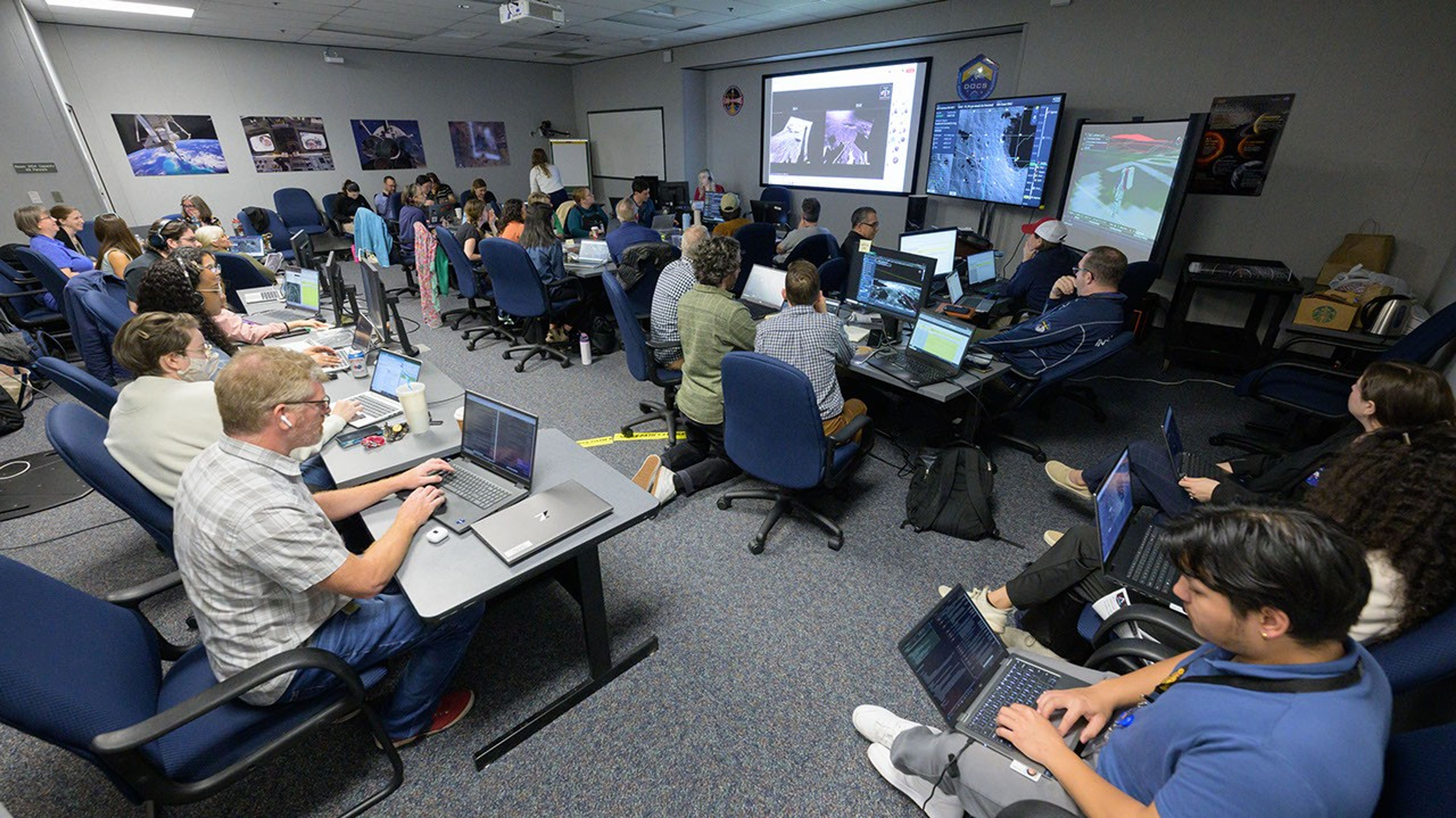 Members of the Artemis III Geology Team and science support team work in a mock Science Evaluation Room during the Artemis III Virtual Reality Mini-Simulation at NASA’s Johnson Space Center in Houston. Video feeds from the surrogate crew members’ VR headsets allow the science team to follow, assess, and direct moonwalks and science activities. The simulation was a test of using VR as a training method for flight controllers and science teams’ collaboration on science-focused traverses on the lunar surface.