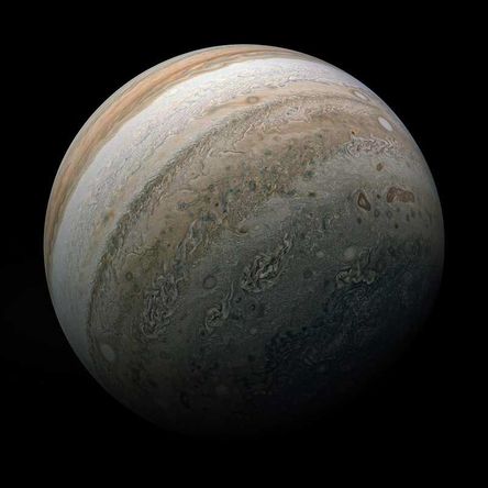 Three-quarters of planet Jupiter is visible, with alternating swirling bands of brown and white present.